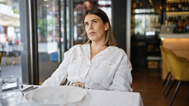 Genç, güzel, İspanyol bir kadın restoranın masasına bakıyor.