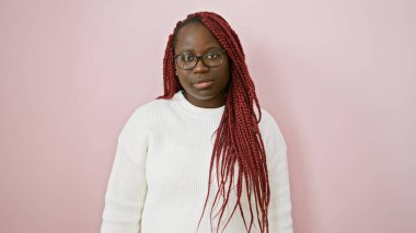 Pembe arka planda gözlük takan, kendine güvenen Afro-Amerikan bir kadının portresi.