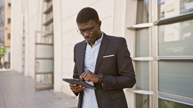 Sokakta tablet kullanan takım elbiseli Afrikalı bir adam.