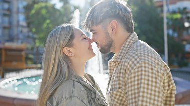 Genç bir çift açık havada kucaklaşır. Güneşli bir parkta sevgi ve yakınlık yayarlar. Romantizm yayarlar.