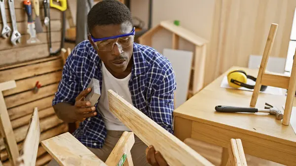 stock image A focused man engaging in woodworking in an organized indoor workshop.