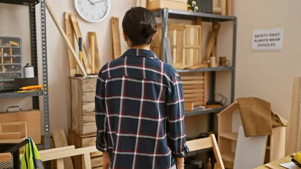 stock image A young asian woman in a workshop, surrounded by carpentry tools, focused on her craft indoors.