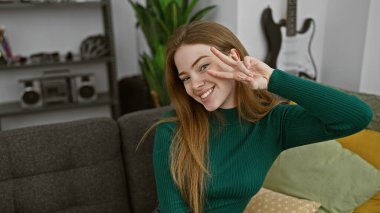 Gülümseyen kadın modern apartman dairesinde barış işareti yapıyor gitar ve bitkilerle..