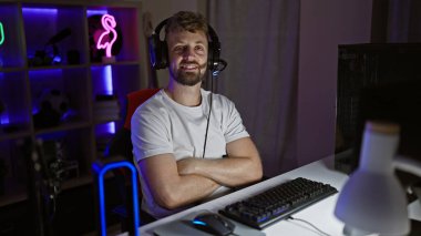 Sakallı yakışıklı genç bir adam geceleri neon ışıkları olan karanlık bir odada oyun oynamaktan hoşlanıyor..