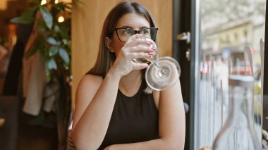 İç mimarisi bulanık, modern bir kafede su içen İspanyol bir kadın..
