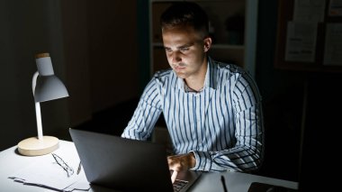 Odaklanmış İspanyol adam geç saatlere kadar bilgisayar ve masa lambasıyla çalışıyor..