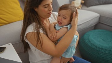 Oturma odasında ağlayan bir çocuğu rahatlatan, evdeki kanepede otururken sevgi ve ilgiyi ifade eden bir kadın.