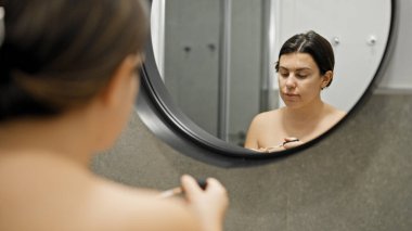 Genç ve güzel İspanyol kadın banyoda makyaj yapıyor.