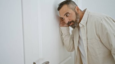 Yakışıklı, yaşlı, gri sakallı bir adam, ilginç bir şekilde ev kapısından içeri bakıyor..