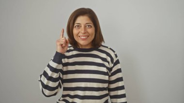 Orta yaşlı, gülümseyen İspanyol bir kadının portresi yukarıya bakıyor, beyaz bir arka planda soyutlanmış..