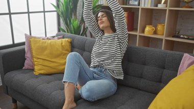 Rahat, genç bir İspanyol kadın rahat bir kanepeye uzanmış çağdaş bir iç fona karşı..