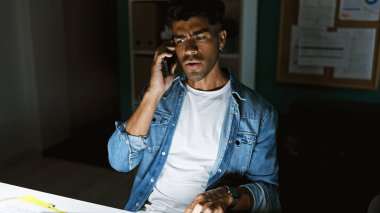 Kot giyen İspanyol adam telefonda konuşuyor.