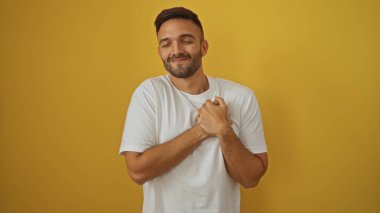 Yakışıklı, sakallı, genç bir İspanyol adam elleri göğsünde sıcacık gülümsüyor..