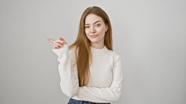 Güzel, genç, sarışın bir kadın beyaz bir arka plana karşı güvenle poz veriyor..