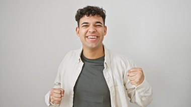 Beyaz arka plan karşısında kıvırcık saçlı neşeli bir genç adam sevinç ve neşe saçıyor..