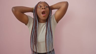 Örgü ören Afro-Amerikalı kadın pembe izole bir arka plana şaşırdığını ifade ediyor.