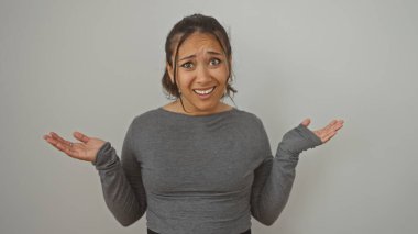 Kafası karışık bir ifadeyle omuz silken İspanyol bir kadın, beyaz bir arka planda izole edilmiş..