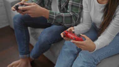 Çift evlerinde oyun oynuyorlar, rahat bir oturma odasında oyun kumandalarıyla bir koltukta oturuyorlar..