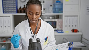 Afrikalı kadın bilim adamı laboratuvar ortamında örnek analiz ediyor..