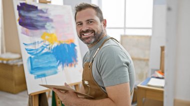 Parlak bir stüdyoda gri saçlı, gülümseyen sakallı adam yakışıklı, olgun sanatçı kişiliğini sergiliyor..