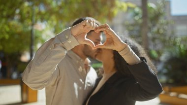 Sevgi dolu bir çift, güneşli bir günde güzel ve sevgi dolu bir anı yansıtan elleri açık bir kalp oluşturur..
