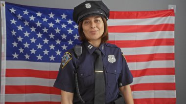 Kendinden emin bir İspanyol polis memuru, Amerikan bayrağının önünde gururla poz veriyor..