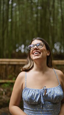 Gözlüklü güzel İspanyol kadın, Kyoto 'nun yemyeşil bambu ormanlarının arasında durup etrafa bakıyor, neşe ve şaşkınlık içinde..