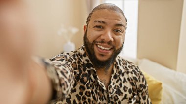 Yakışıklı, sakallı, Afro-Amerikan bir adam yatak odasının içinde selfie çekiyor..