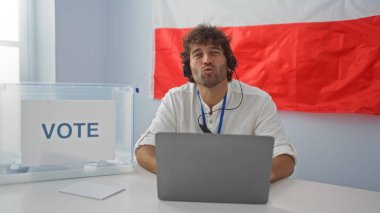 Young man indoors at a voting station with polish flag working on laptop wearing headset clipart