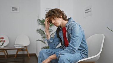 Sakallı, kot giyen, modern bir salonda düşünceli, genç, İspanyol bir adam..