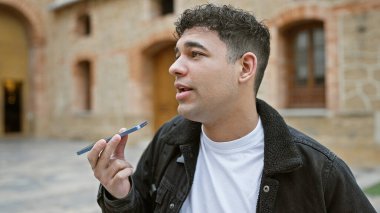 Şehir sokağında ses kayıt cihazına konuşan yakışıklı bir adam..