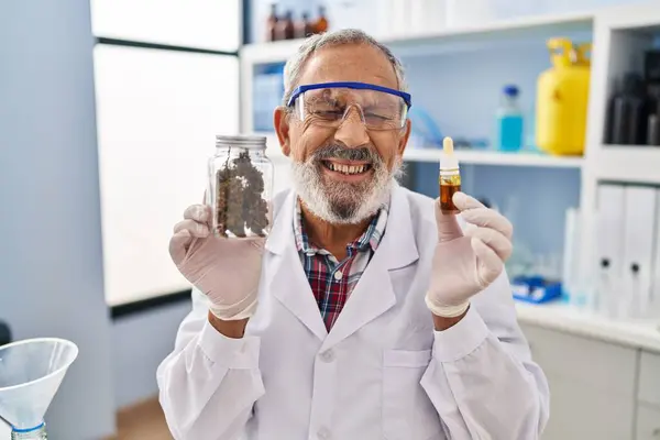 stock image Joyful senior man laughing hard at a funny joke while holding his cannabis medicine in the lab, his smile radiating positivity and confidence.