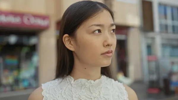 stock image Chinese woman outdoors on a city street expresses thoughtful emotion while standing against an urban backdrop in china.