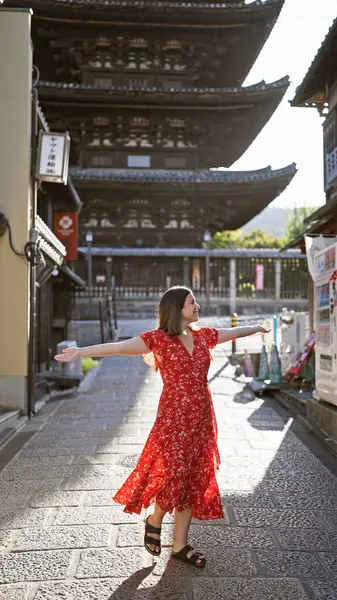 stock image Confident, beautiful hispanic woman reveling with open arms, smiling while looking around at the charm of kyoto's traditional gion streets