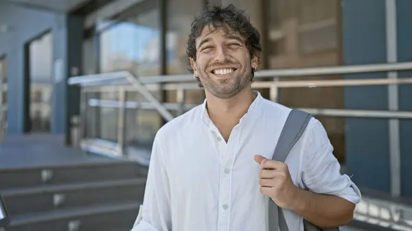 stock image Handsome bearded man with a casual shirt and messenger bag smiling on a sunny city street.