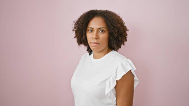 Pembe arka planda kıvırcık saçlı Afrikalı Amerikalı kadın.
