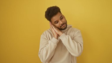 Yakışıklı adam, canlı sarı bir arka planda huzurlu bir andan zevk alıyor. Huzur ve memnuniyet yayıyor..