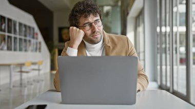 Modern ofisteki laptopta sakallı yakışıklı, düşünceli bir adam..