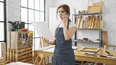 Kot önlüklü orta yaşlı bir kadın elinde parlak marangozluk atölyesinin planlarını tutuyordu.
