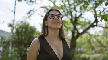 Neşeli İspanyol kadın neşe içinde poz veriyor, gözlük parıldıyor, geleneksel Kyoto sokaklarının ortasında dikiliyor Japon mimarisi tarafından büyüleniyor, güzel gülüşü kendine güvenini yayıyor..