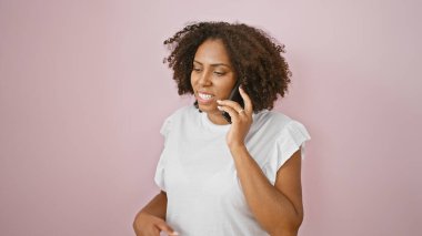 Pembe arka planda telefonla konuşan Afrikalı Amerikalı kadın.