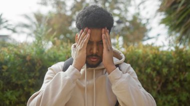 Doğada başı açık gezen stresli Afrikalı Amerikalı bir adam.