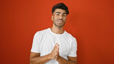 Yakışıklı genç adam canlı kırmızı bir arka planda el ele yalvarıyor..