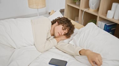 Genç bir adam rahat bir yatak odasında huzur içinde uyuyor. Ev ortamında rahatlık ve rahatlık tasvir ediyor..