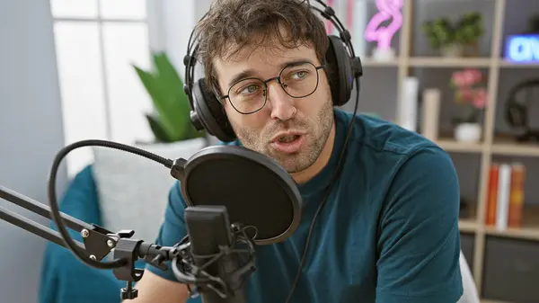 stock image Hispanic man with beard speaking into microphone in radio studio setup indoors.