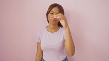 Kendine güvenen Afro-Amerikan kadın, basit, doğal bir görünüş, ciddi bir ifade. Pembe arka planda tek başına dikiliyor. Samimi bakışları kamerayla buluşuyor..