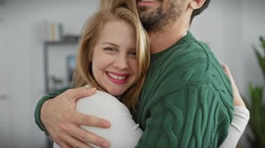 Sevecen bir kadın ve erkek sıcak bir oturma odasında sevgi dolu bir şekilde kucaklaşıp, bir an olsun mutluluğu paylaşıyorlar..