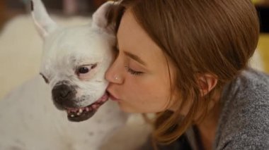 Genç sarışın bir kadın sıcak bir yatak odasında köpek dişini öpüyor..