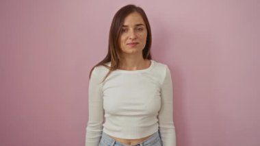 Genç sarışın kadın ayakta duruyor ve mutlu zaferi kutluyor kazanan bir gülümseme ve heyecanlı bir ifadeyle izole edilmiş pembe arka planda el kaldırıyor.