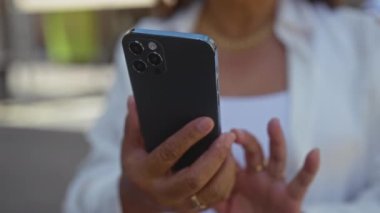 Açık bir şehir caddesinde orta yaşlı bir kadının elleri akıllı telefon tutuyor..